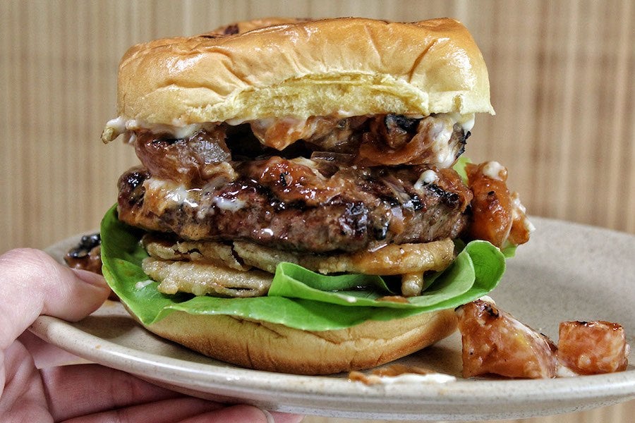 A thick burger sits on Bibb lettuce and is piled high with toppings.