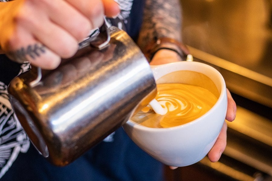 A barista pours foam atop an espresso drink at Diesel Cafe in Somerville