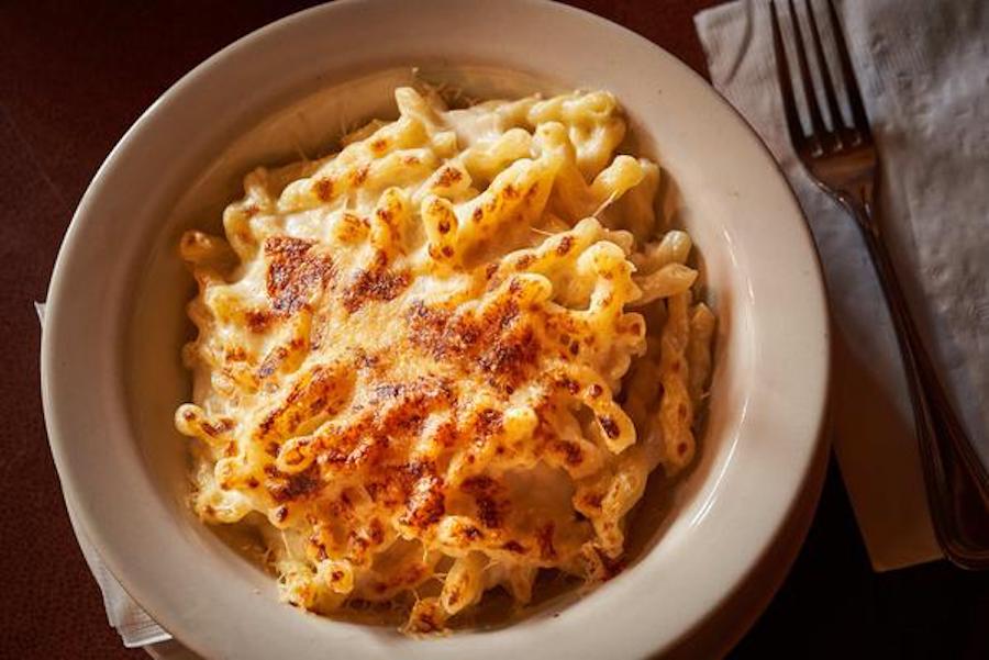 Overhead view of a white bowl full of mac and cheese, the cheese slightly browned.
