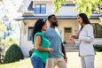 couple with real estate agent in front of house