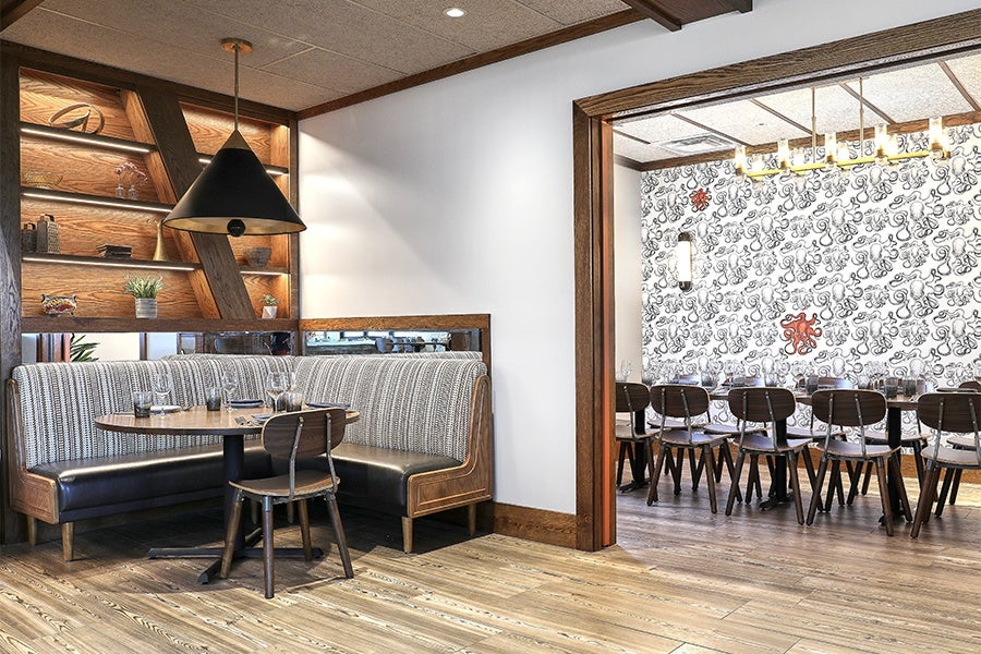 A restaurant interior featuring bright white walls, wooden accents, and octopus wallpaper.