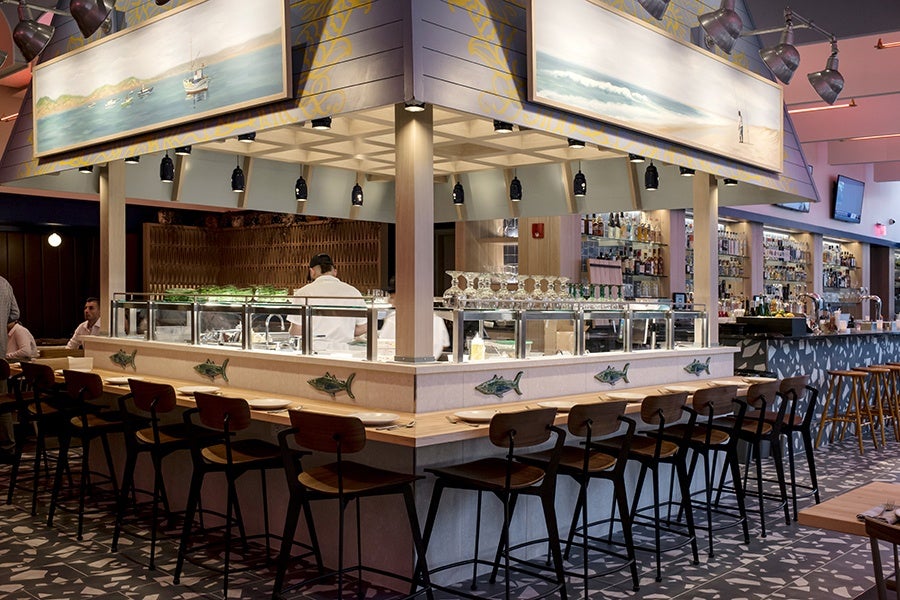 Seats surround an open kitchen area. The decor is beach-themed.