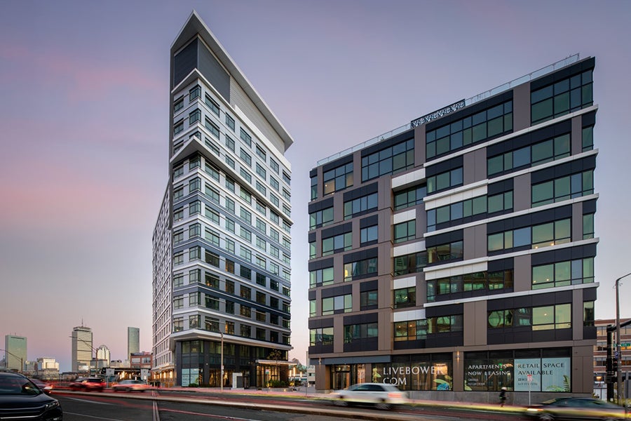 Two tall buildings rise next to a busy city street.