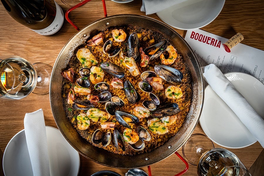 Overhead view of a large pan of seafood paella, packed with mussels, shrimp, and more.