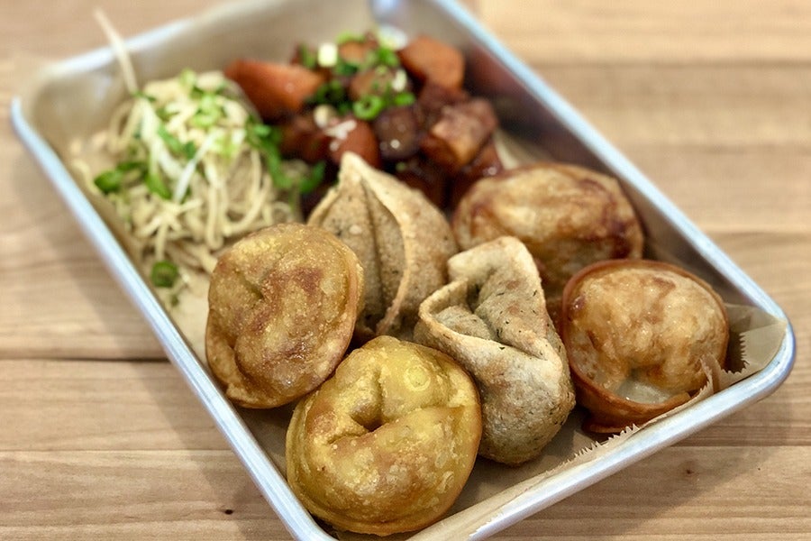 Several types of golden-brown dumplings are nestled together on a small silver tray.