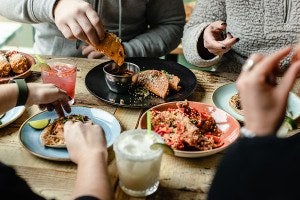 Several people are gathered around a table eating tacos and drinking margaritas.