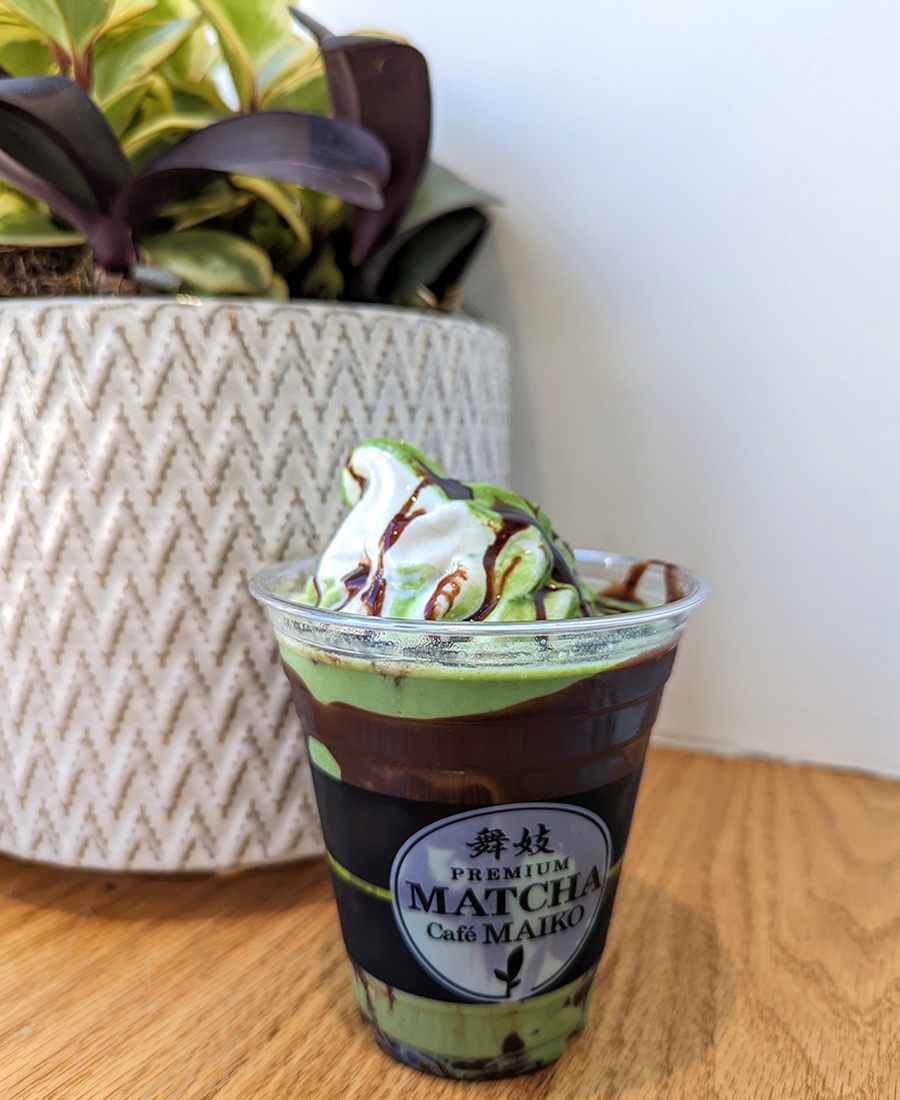 A plastic cup is filled with chocolate sauce and a twist of green and white soft serve.