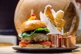 A thick cheeseburger with tomato and lettuce is accompanied by thick steak fries.