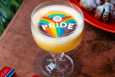 A drink is garnished with a rainbow topping that says Pride and has a small logo of the venue Flight Club.