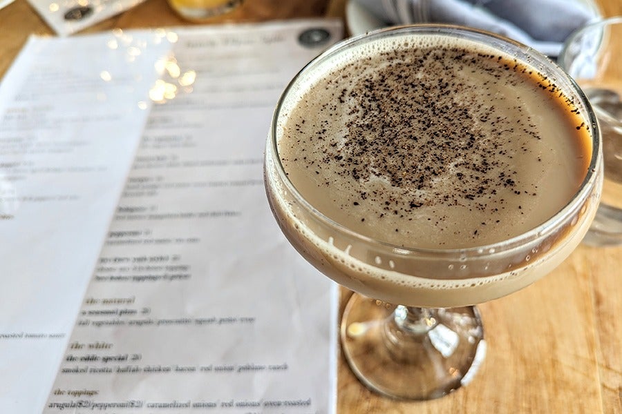 An espresso martini with a restaurant menu visible in the background.