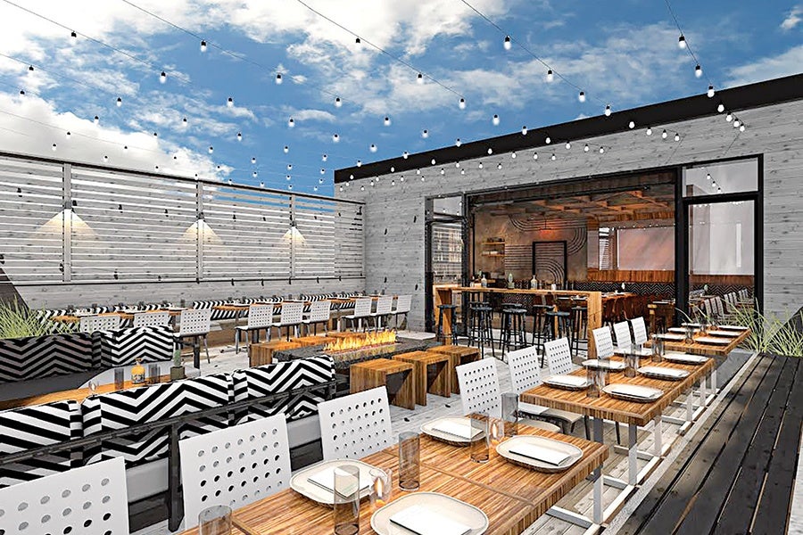 A restaurant roof deck features string lights, table and lounge seating, and blue sky.