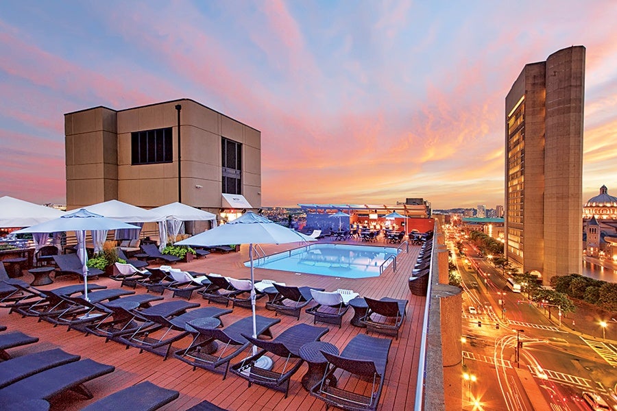 Sunset over a rooftop pool high up in a city.