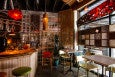 A small restaurant space is filled with an eclectic mix of furniture and decor, including a curtain made of long pieces of bamboo.
