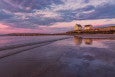 The sun sets over an Atlantic beach with two little shacks sitting on the shore.