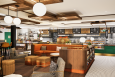 A cafe rendering shows a big orange couch, a black-and-white tiled floor, and accents of green and light wood.