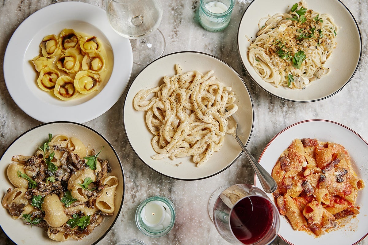 Overhead view of five different pastas on a white marble table.