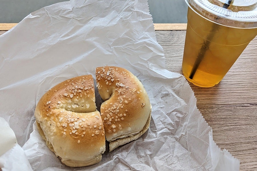 A sliced bagel, topped with a sprinkling of salt, sits on white tissue paper.