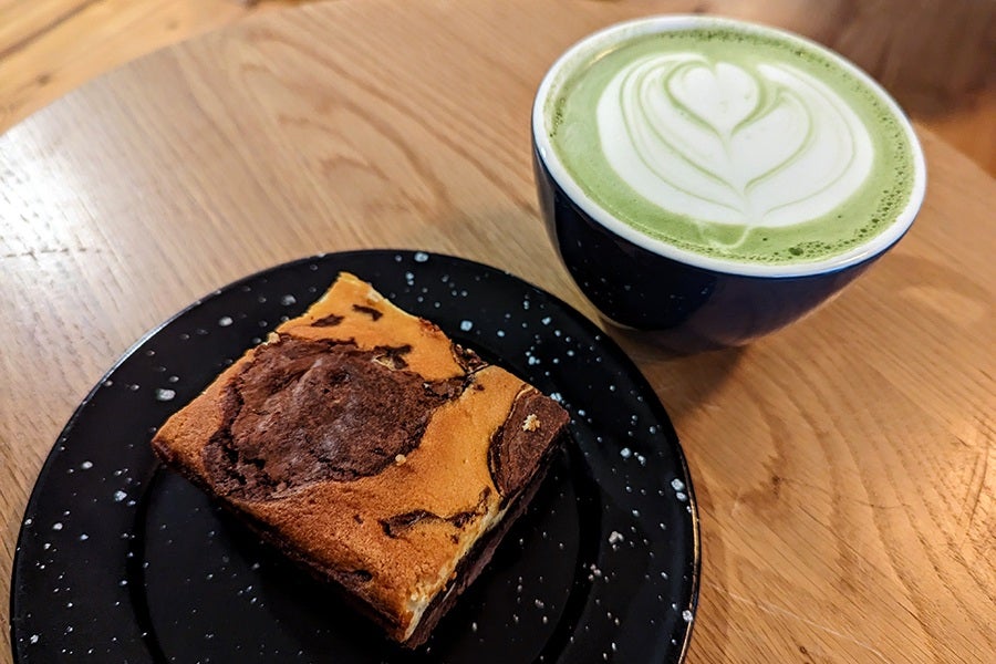 A green latte and marbled brownie sit on a wooden table.