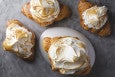 Overhead view of four croissants, each topped with a big dollop of toasted meringue.