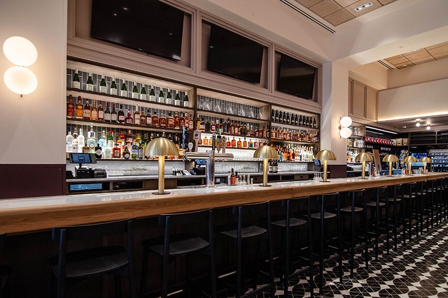 An elegant restaurant bar with gold lamps and a white marble top.