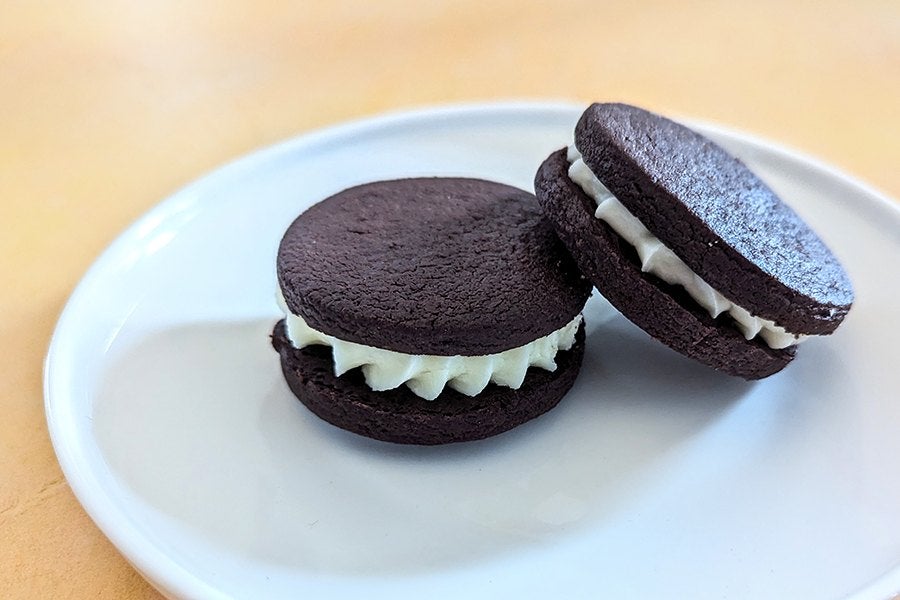 Two bakery-made Oreo-style cookies sit on a white plate.