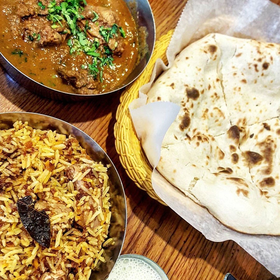 Overhead view of Indian food, including naan, a rice-based dish, and a brown curry.