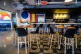 A restaurant interior features colorful murals and neon signage reading Mothership.