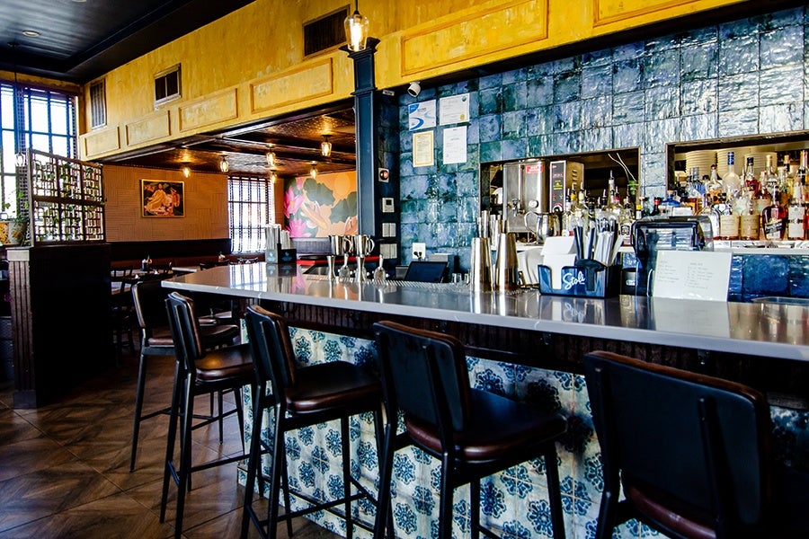 A restaurant dining room includes a bar with distinctive blue tiling.