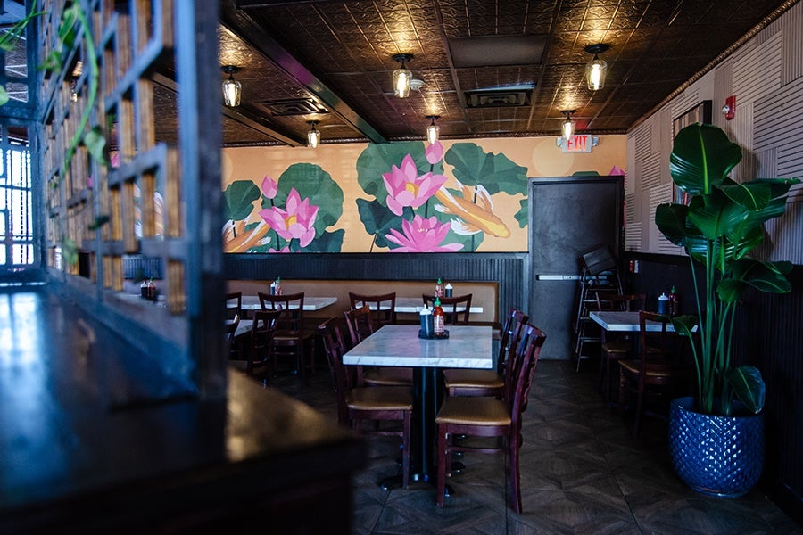 A restaurant dining room features a large mural of koi swimming among water lilies.