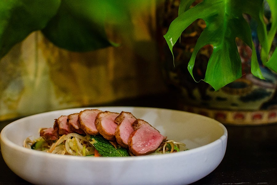 Thin slices of duck sit atop an herb salad.