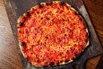 Overhead view of charred, thin-crust, New Haven-style pizza with tomato sauce and mozzarella.