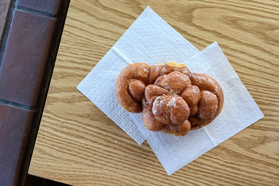 Overview of a uniquely bowtie-shaped glazed doughnut on a table.