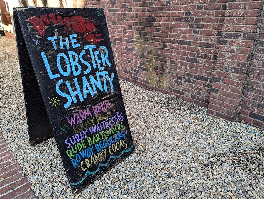 A chalkboard sign for a restaurant reads: The Lobster Shanty. Warm Beer, Surly Waitresses, Rude Bartenders, Rowdy Regulars, Cranky Cooks.