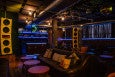 Interior of a bar with big speakers, lounge furniture, a disco ball, and a neon banana.