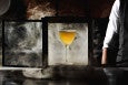 A yellow cocktail is presented in a glass box full of smoke.