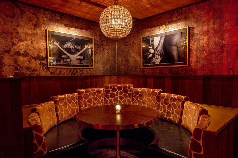 A giraffe-print banquette and black-and-white photography of a person near a piano.