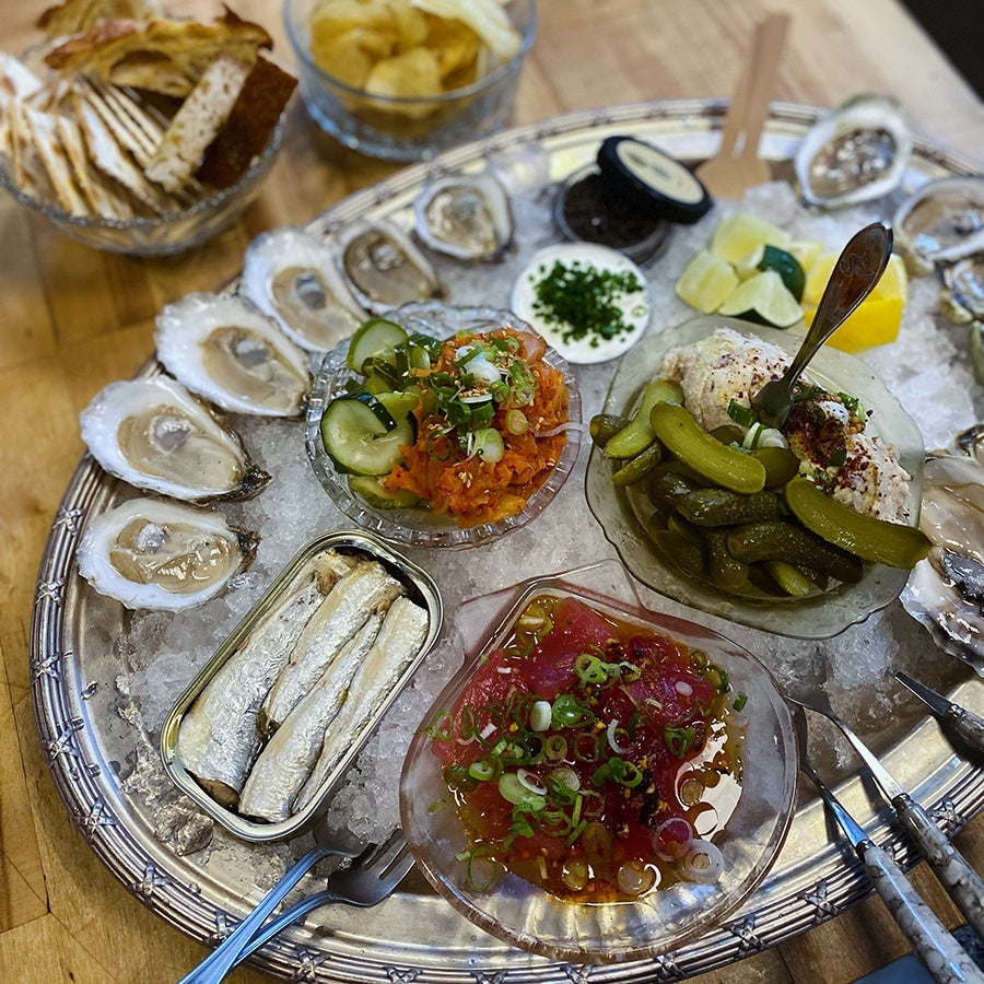A seafood platter features a variety of raw and preserved seafood items and accoutrements on ice.