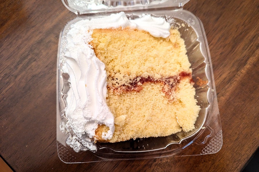 A slice of vanilla-frosted cake has a strip of guava jam in the middle.