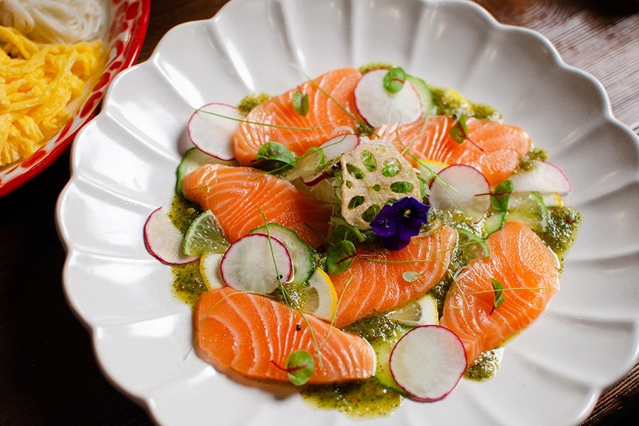 Salmon crudo with thinly sliced radishes, micro greens, lime, and a green sauce.