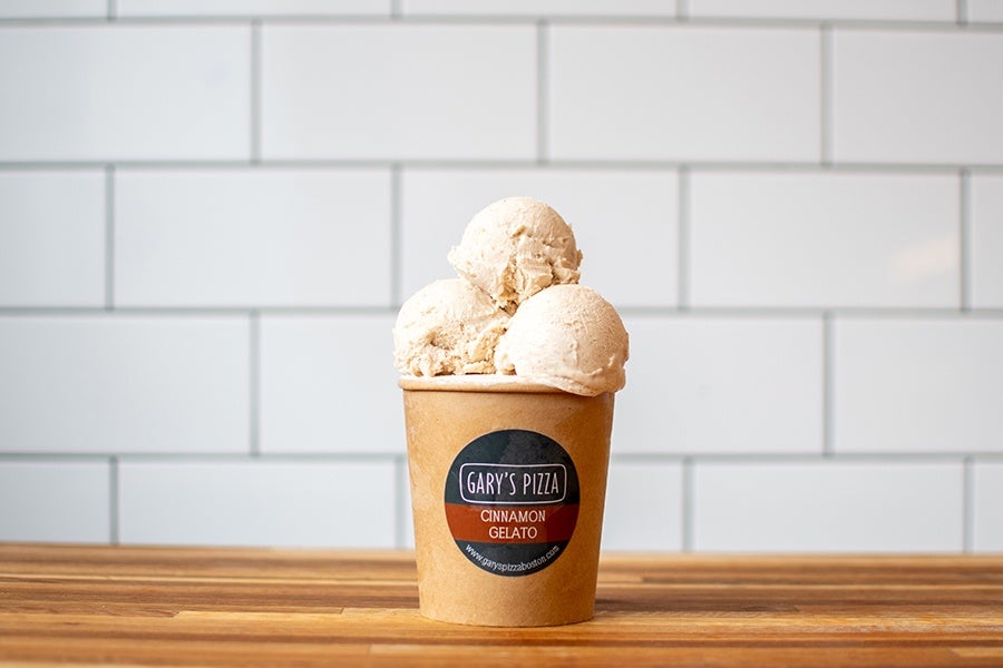 A pint of gelato is open to reveal three off-white scoops of cinnamon.