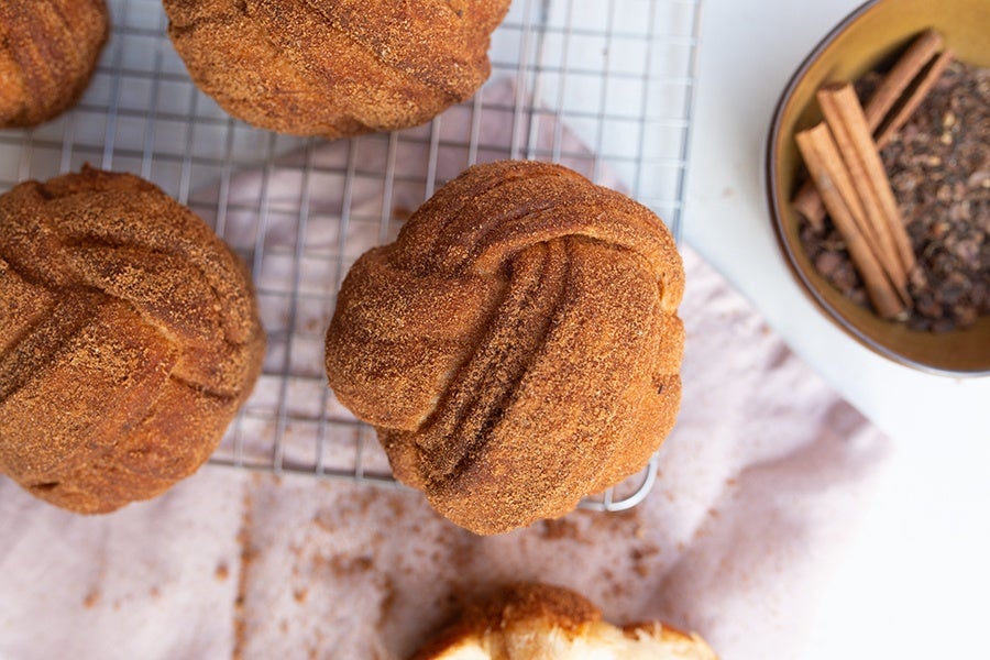 Bun-shaped pastries are covered with a dusting of light brown spices.