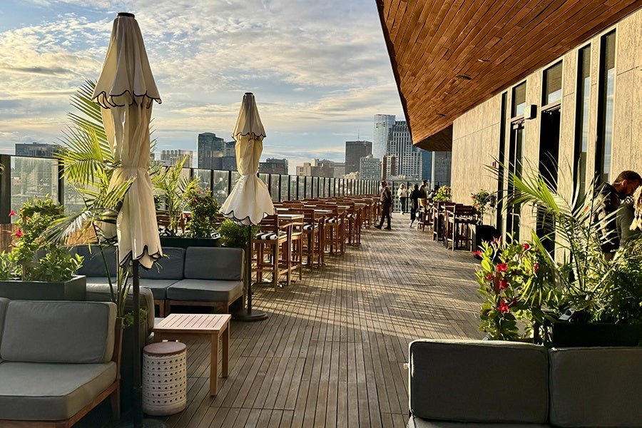 A spacious rooftop restaurant and bar in the middle of a city, photographed on a sunny day.