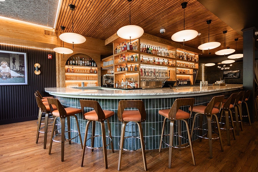 A curved bar covered in dark green vertical tiles inside a restaurant.
