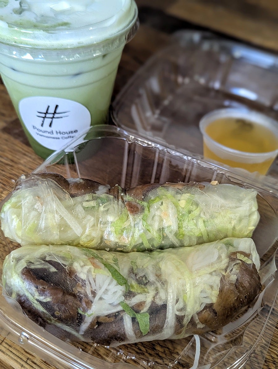 An iced matcha latte and pork-and-rice-noodle-stuffed fresh rolls in takeout packaging.