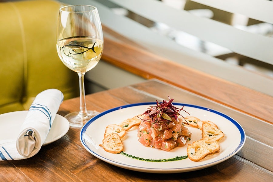 Elegant tuna tartare with a glass of wine on a restaurant table.