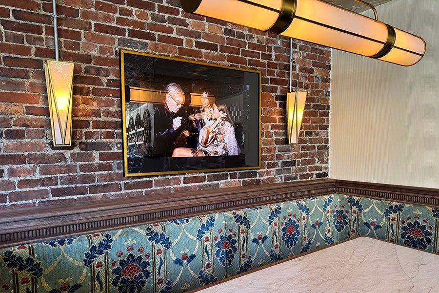 A restaurant interior shot features an upholstered restaurant booth and a Studio 54 photo on a brick wall.