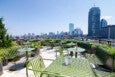 A rooftop patio features green outdoor furniture and skyline views of Boston.
