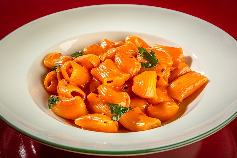 A bowl of thick rigatoni in a red-orange sauce.