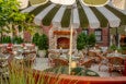 An Italian-inspired large restaurant patio with green-and-white-striped umbrellas and a fireplace.