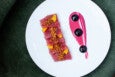 Overview of an elegantly plated tuna crudo garnished with a bright pink swoosh of beet puree dotted with three black dollops of black garlic puree.